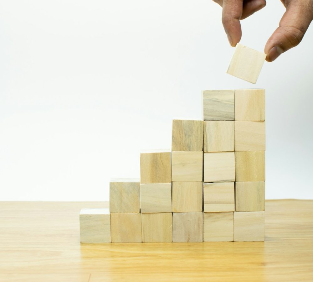 A person placing a piece of wood into a pyramid